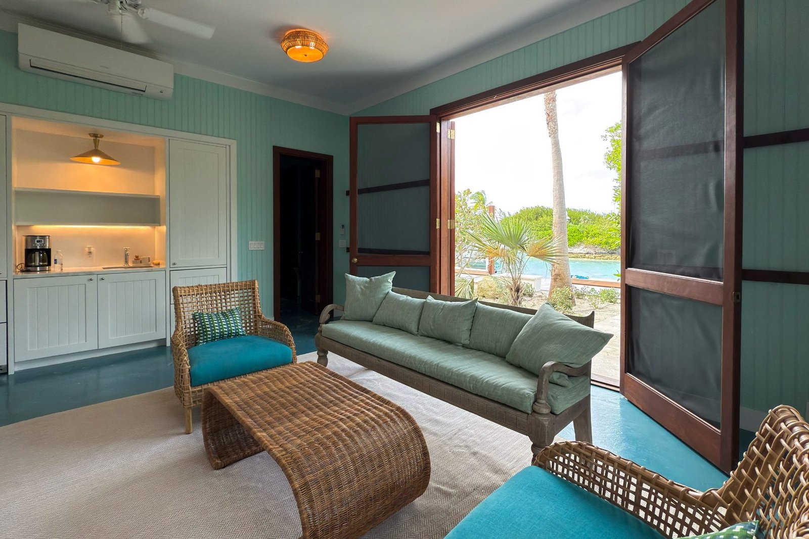 A guest sitting room with kitchenette and doors to the water
