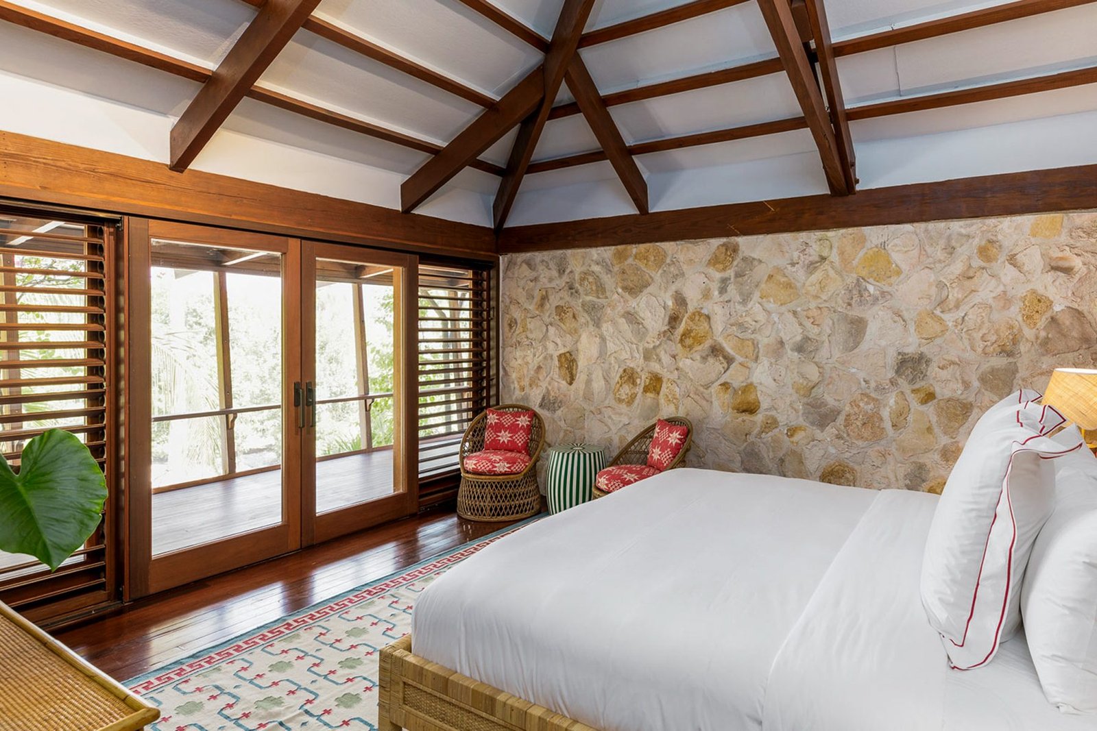 A bedroom with stone wall and doors onto the deck