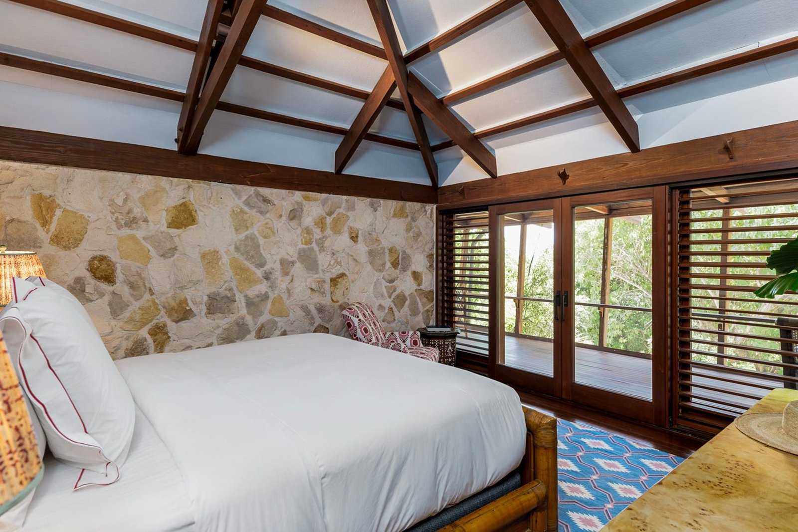 A bedroom under a vaulted beamed ceiling