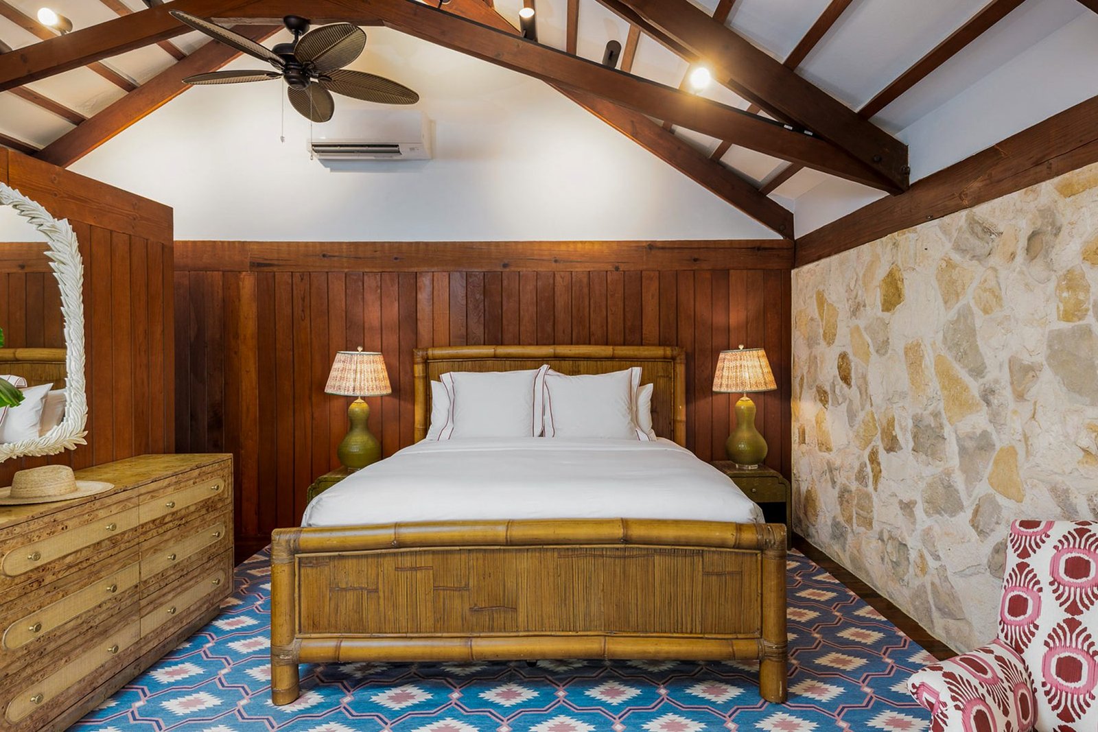 A bedroom with bamboo bed, timber panelling and stone
